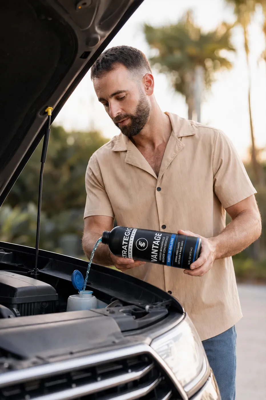 Pouring VANTAGE washer concentrate into a reservoir under a lifted hood